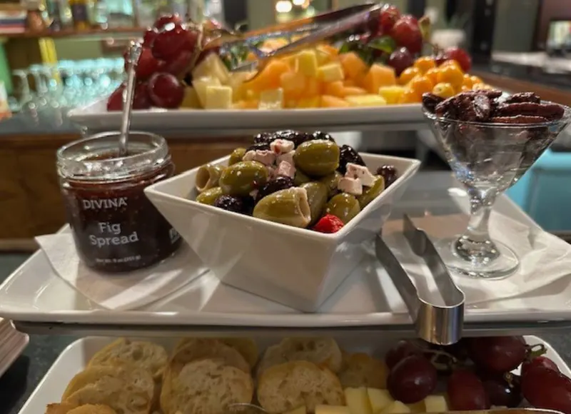 A catering spread of olives, cheese, fruit, crostini and fig spread